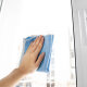 Hand wischt mit einem blauen Microfasertuch eine Fensterscheibe ab