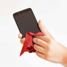 Eine Person reinigt den Bildschirm eines Smartphones mit einem roten Microfaser Brillentuch.