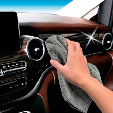 Ein graues Microfaser Waffeltuch wird verwendet, um das Armaturenbrett im Inneren eines Autos zu reinigen.
