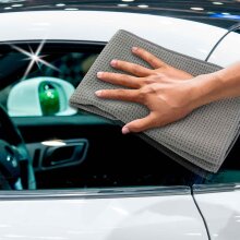 Ein graues Microfaser Waffeltuch wird verwendet, um die Autofenster zu reinigen.