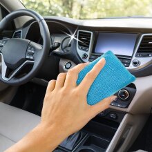 Eine Person hält einen Classic Scheibenschwamm und reinigt das Armaturenbrett im Inneren eines Autos.