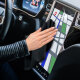 Hand wischt mit einem schwarzen Soft-Microfasertuch über den Touchscreen eines Autos.